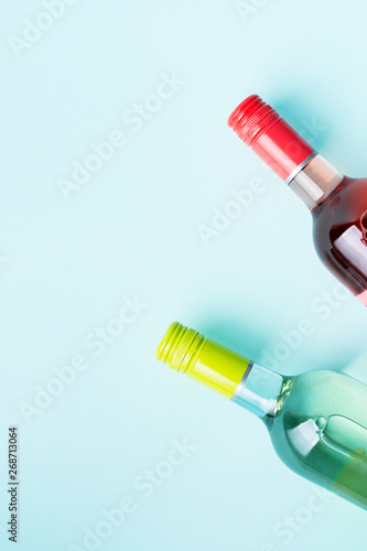 Screw bottle foil caps in different bright colors of white and rose wine bottles on blue background with copy space. Minimal abstract colorful mockup concept of alcohol beverage. Flat lay. © PINKASEVICH