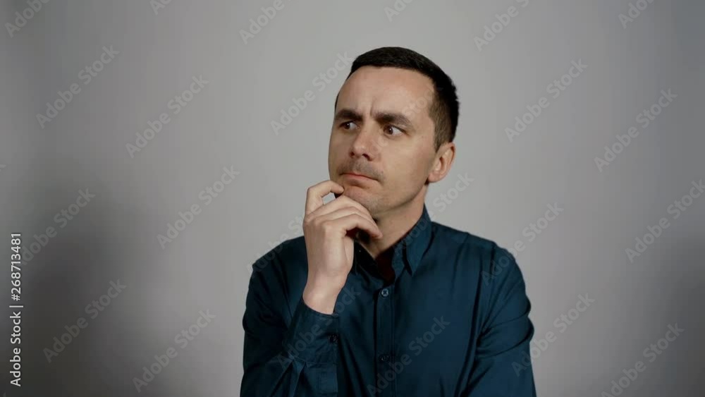 Closeup portrait of a young business man thinking into the camera on a white background. Guy thoughtfully puts his finger near the mouth. Charismatic actor play concept of emotions Closeup portrait of a young business man thinking into the camera on a white background. Guy thoughtfully puts his finger near the mouth. Charismatic actor play concept of emotions