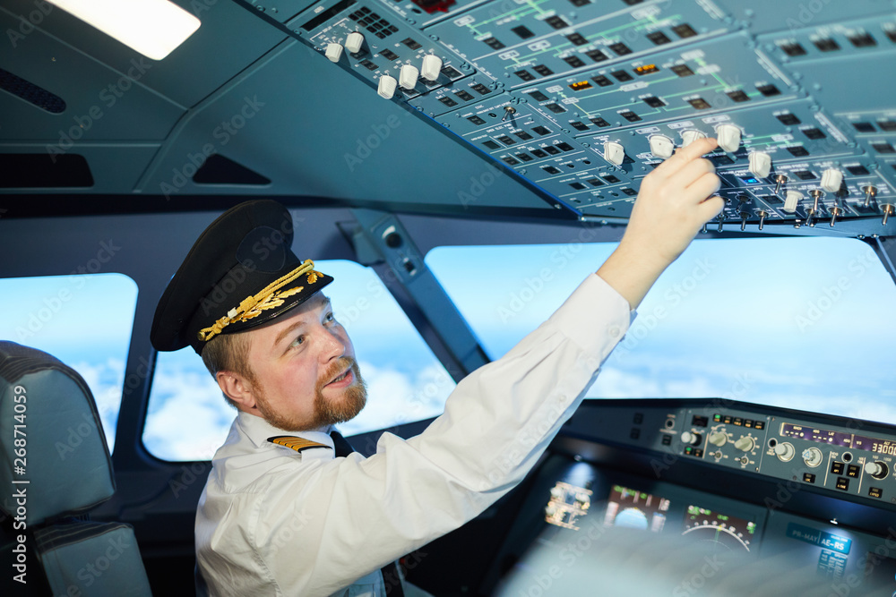 Serious chubby bearded professional pilot in captains cap sitting in ...