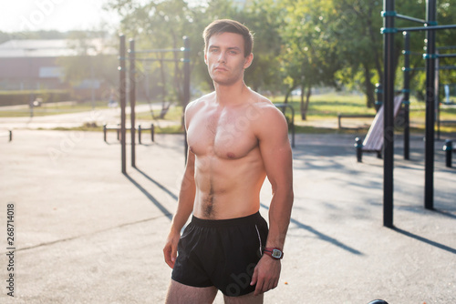 Fitnes man posing on street fitness station showing his muscular body © undrey