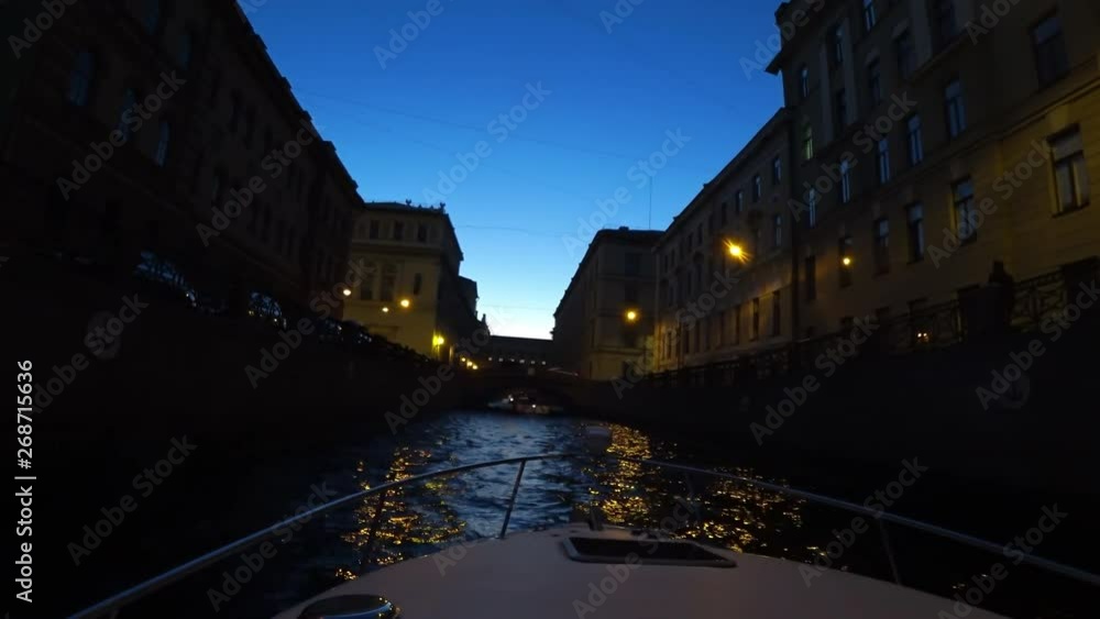Night walk through the canals of St. Petersburg, Russia. On the river pass passenger boats. The ship turns on the water and floats towards the bridge Night walk through the canals of St. Petersburg, Russia. On the river pass passenger boats. The ship turns on the water and floats towards the bridge