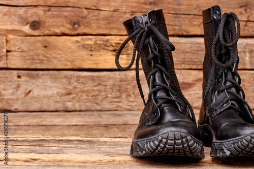 Close up pair of black boots. Wooden desk background.