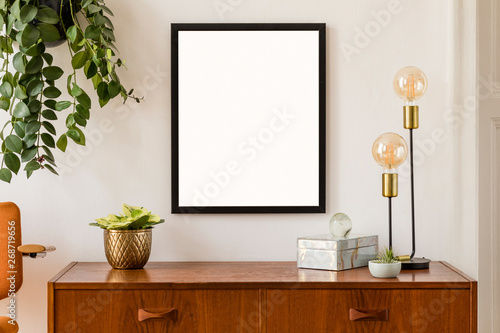 Stylish room of home interior with black mock up frame with vintage accessories, plant, box, orange chair and gold table lamp. Cozy home decor. Minimalistic concept. Modern composition of cupboard. © FollowTheFlow