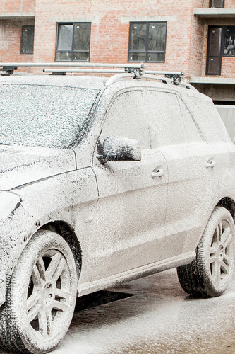 Car wash with foam in car wash station. Carwash. Washing machine at the station. Car washing concept. Car in foam photo