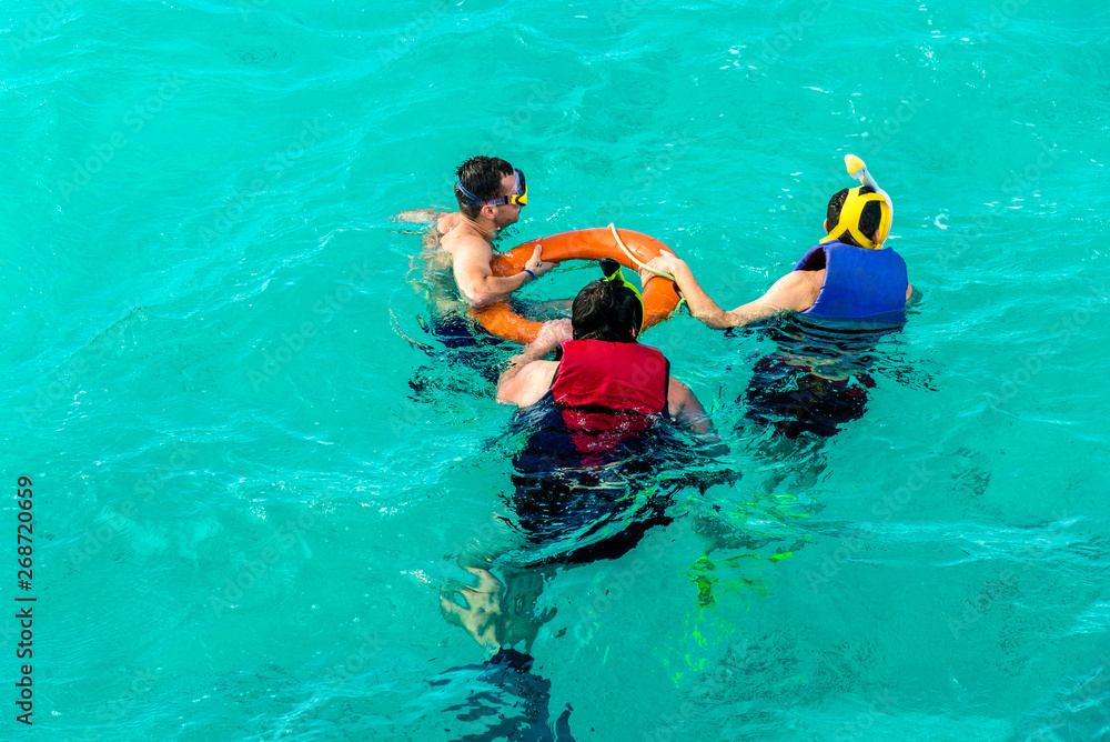 Leisure and sports, several people snorkeling in the blue sea