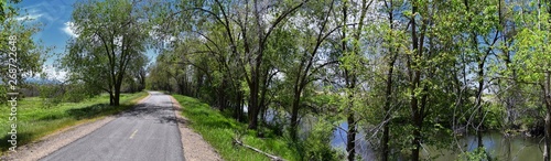 Jordan River Parkway Trail, Redwood Trailhead bordering the Legacy Parkway Trail, panorama views with surrounding trees and silt filled muddy water along the Rocky Mountains, Salt Lake City, Utah. 