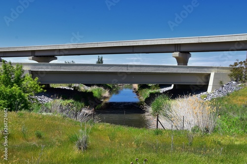 Jordan River Parkway Trail, Redwood Trailhead bordering the Legacy Parkway Trail, panorama views with surrounding trees and silt filled muddy water along the Rocky Mountains, Salt Lake City, Utah. 