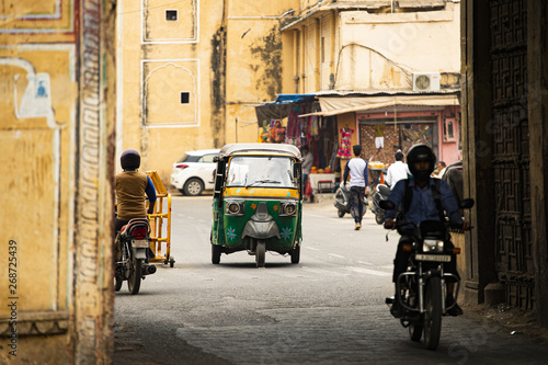 Obraz na płótnie City life with Auto rickshaw (also known as Tuc Tuc) and motorbikes through the streets of Jaipur. Jaipur is the capital of the Indian state of Rajasthan, India. w salonie