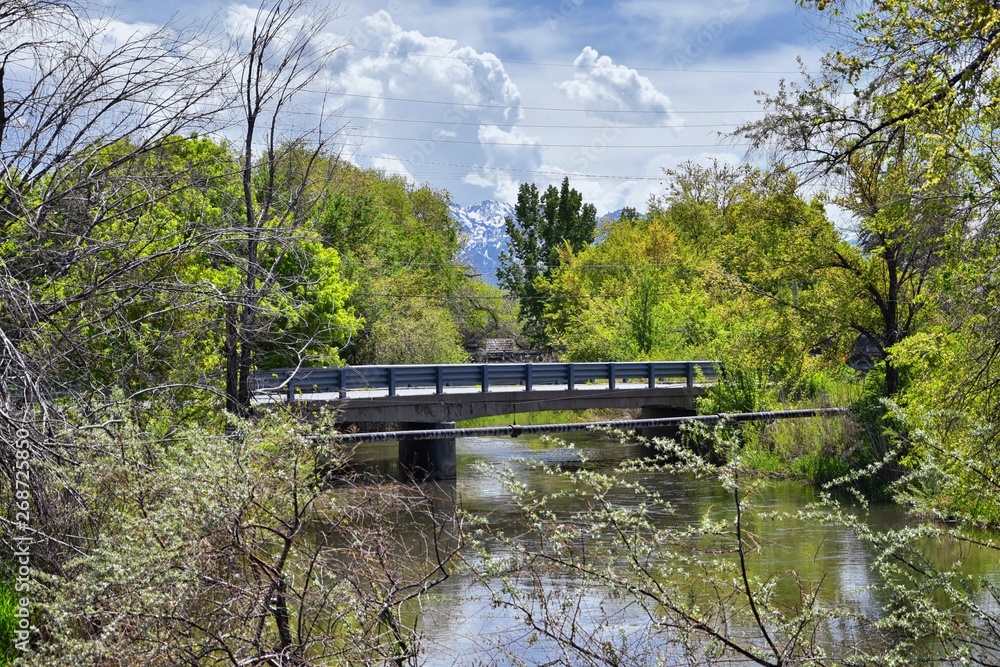 Jordan River Parkway Trail, Redwood Trailhead bordering the Legacy Parkway Trail, panorama views with surrounding trees and silt filled muddy water along the Rocky Mountains, Salt Lake City, Utah. Jordan River Parkway Trail, Redwood Trailhead bordering the Legacy Parkway Trail, panorama views with surrounding trees and silt filled muddy water along the Rocky Mountains, Salt Lake City, Utah.