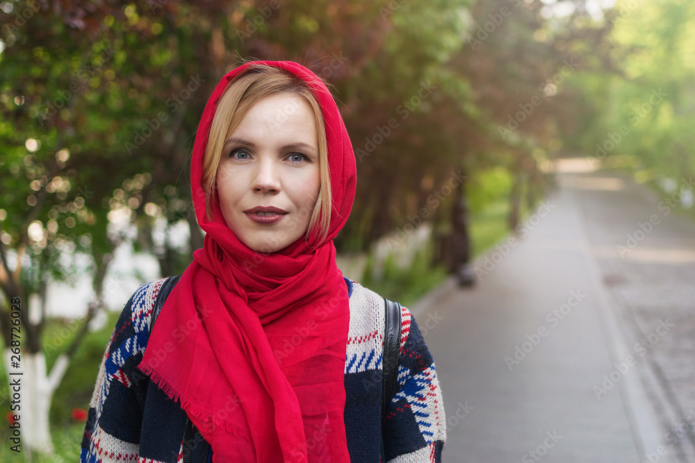 A middle aged woman with a red veil on her head in a park in summer. A middle aged woman with a red veil on her head in a park in summer.