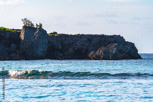 Coastal tropical sea water cliffs on sunny summer day on Caribbean island. Low tide and small waves on the ocean on holiday vacation weekend afternoon. Scenic coastline landscape in Portland Jamaica.