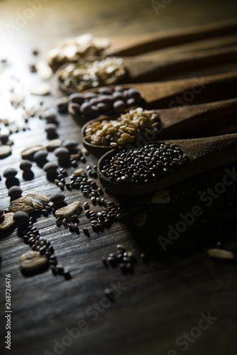 wooden spoons with cereals and seeds on wooden background