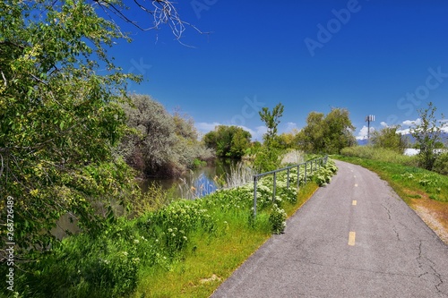 Jordan River Parkway Trail, Redwood Trailhead bordering the Legacy Parkway Trail, panorama views with surrounding trees and silt filled muddy water along the Rocky Mountains, Salt Lake City, Utah.  photo