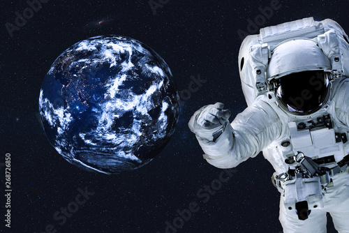 Astronaut near the Earth planet at night with city lights of Solar system. Science fiction. Elements of the image are furnished by NASA
