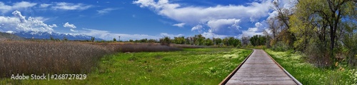 Jordan River Parkway Trail, Redwood Trailhead bordering the Legacy Parkway Trail, panorama views with surrounding trees and silt filled muddy water along the Rocky Mountains, Salt Lake City, Utah. 