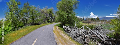 Jordan River Parkway Trail, Redwood Trailhead bordering the Legacy Parkway Trail, panorama views with surrounding trees and silt filled muddy water along the Rocky Mountains, Salt Lake City, Utah.  photo