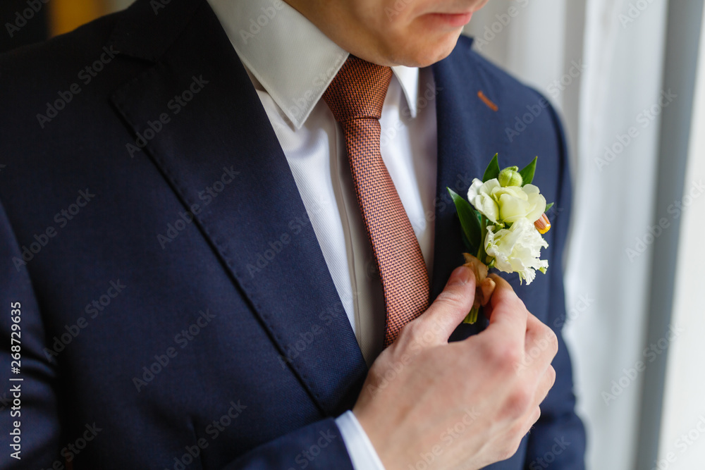 Elegant businessman sewed to order suit, straightens his tie in an expensive hotel, going to a meeting