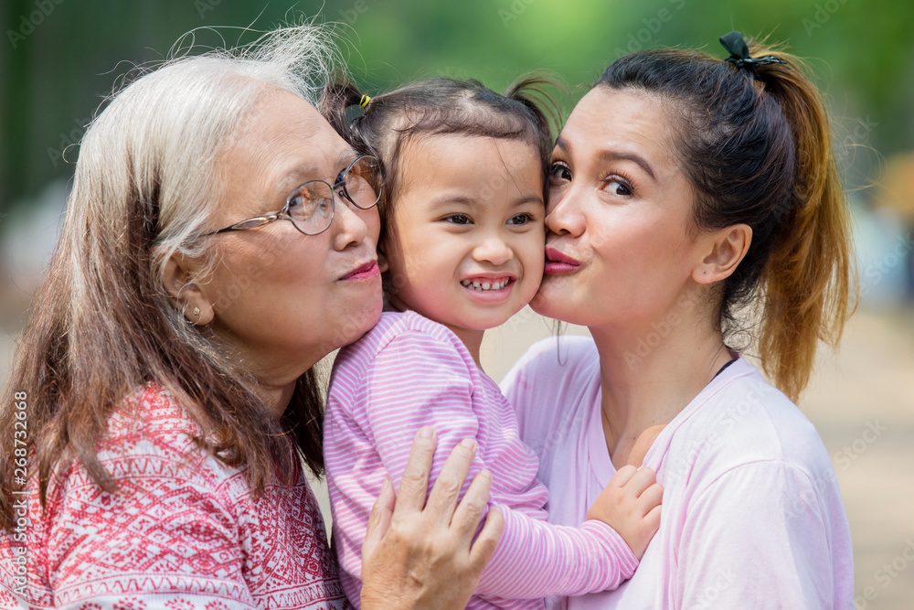 Happy little girl kissed by her mother and granny Happy little girl kissed by her mother and granny