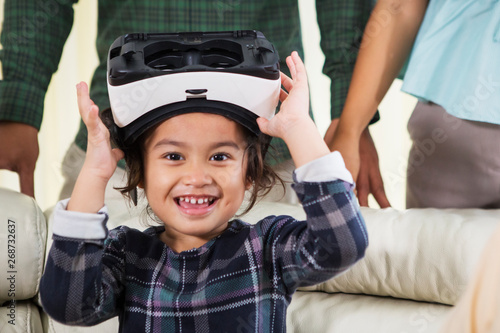 Happy little girl holding a virtual reality goggles