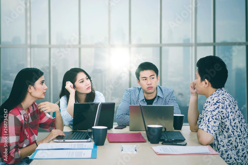 Young man discusses with his partners in the office