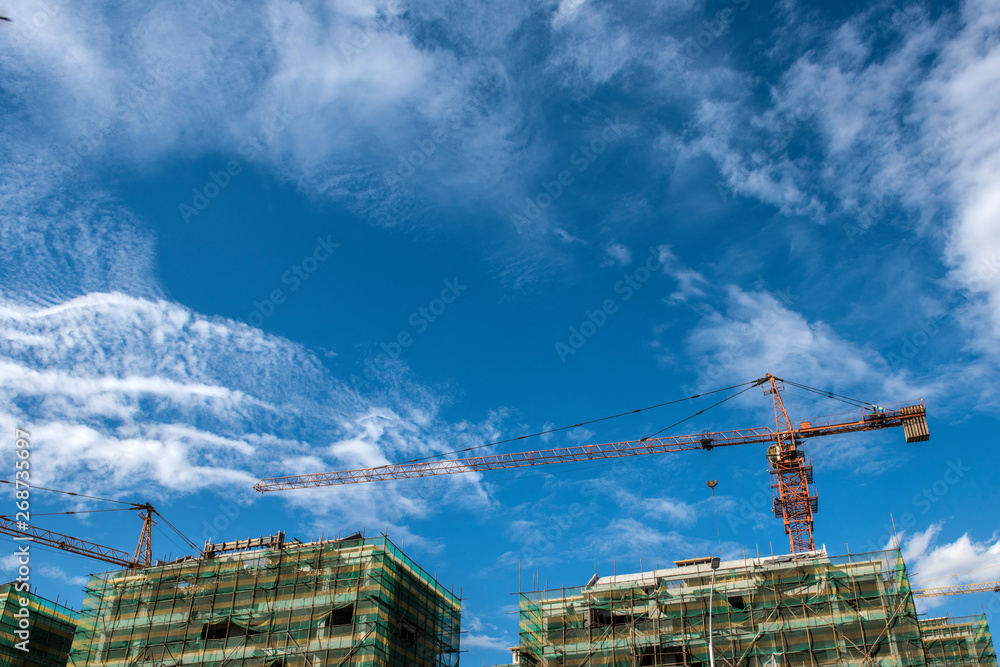 Tower crane at the construction site of blue sky and white clouds. Tower crane at the construction site of blue sky and white clouds.