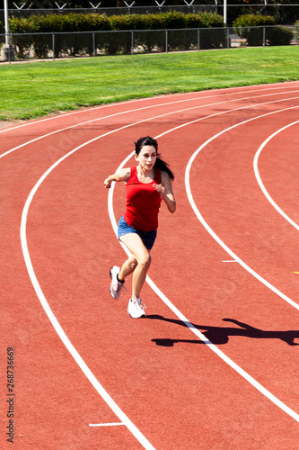 Teen Hispanic Woman Running On Track Shorts And Top