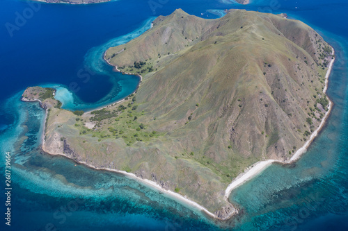 Seen from a bird's eye view, the idyllic island of Gili Darat is surrounded by a coral reef in Komodo National Park, Indonesia. This area is known for its marine biodiversity as well as its dragons.