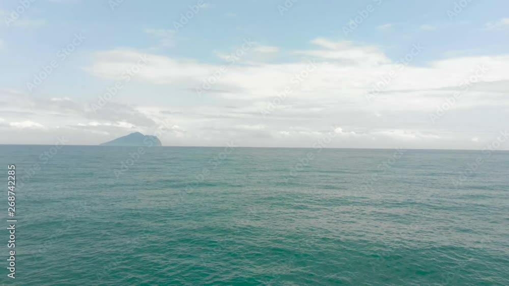 AERIAL: Fly Low Over Ocean Water With Island on Horizon AERIAL: Fly Low Over Ocean Water With Island on Horizon