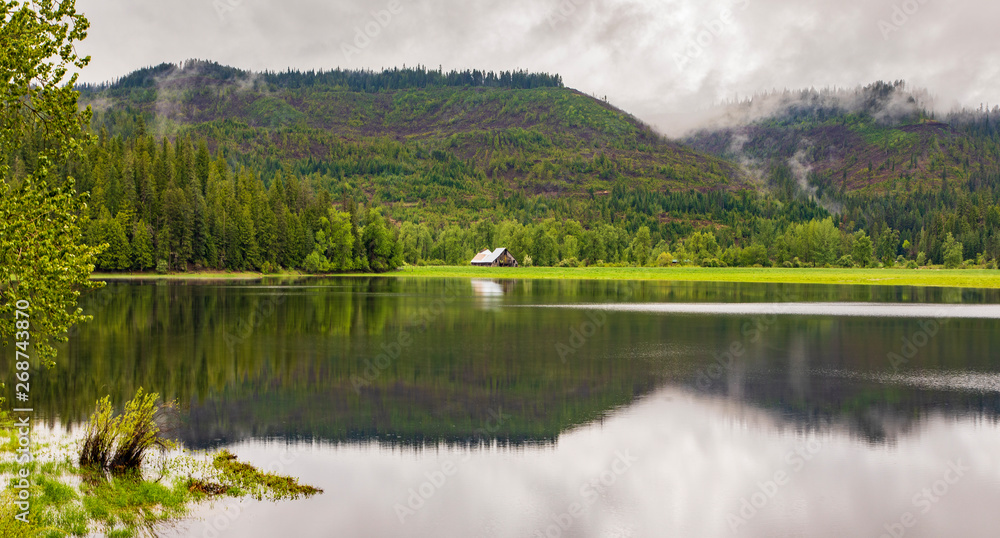 Naklejka premium Barn in the mountains from a distance across a lake