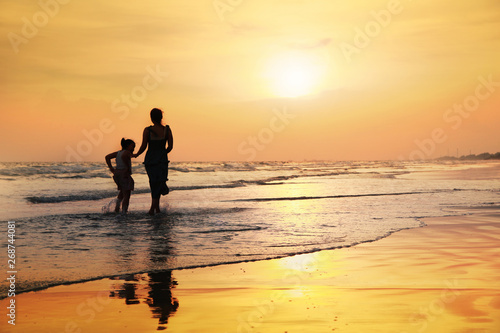 Mother and girl on the beach at sunset background