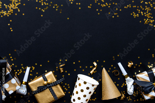 Obraz na płótnie Gift boxes in various gold pattern wrapping papers and party accessories over star shaped golden sequins on a black background. w salonie