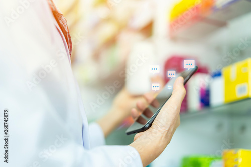 Close up hand of Woman pharmacist holding prescription checking medicine with client online, Social media,social network with smart phone in pharmacy. concept of technology, service, healthcare,life.