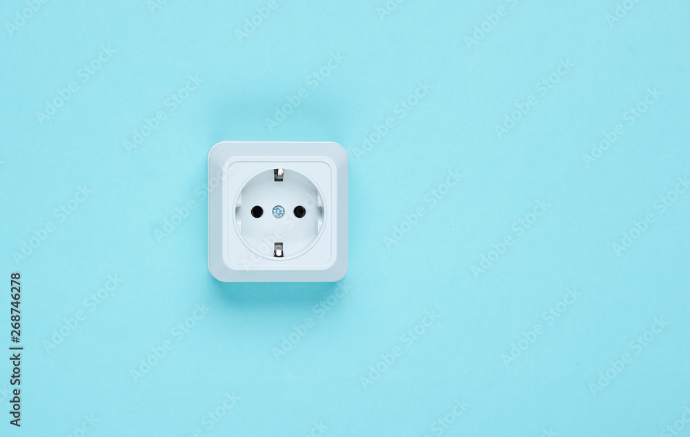 White plastic power socket on blue background. Wall with copy space. Minimalism White plastic power socket on blue background. Wall with copy space. Minimalism