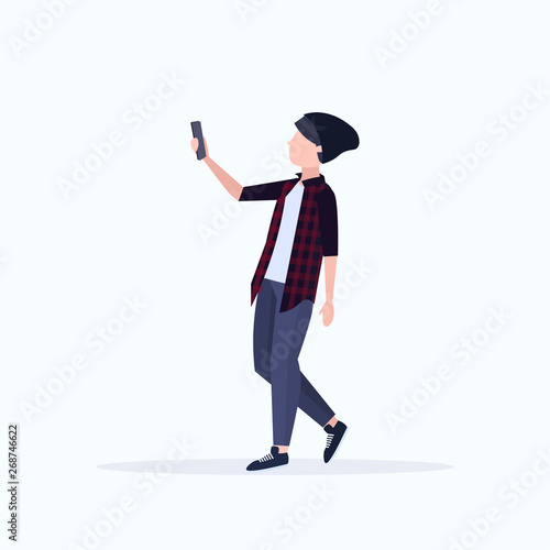 man taking selfie photo on smartphone camera casual male cartoon character in hat posing on white background flat full length
