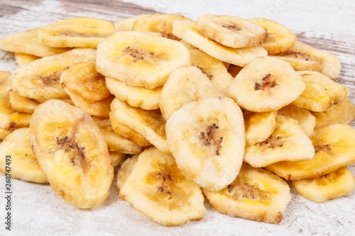 Dried organic banana chips on rustic board