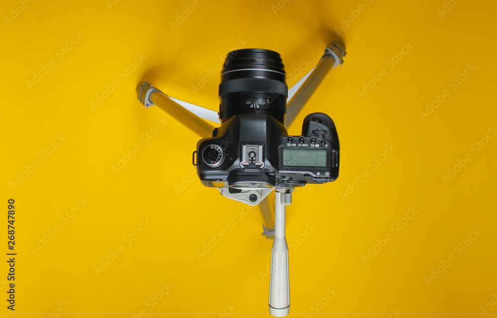 Modern digital camera with tripod on yellow background. Top view Modern digital camera with tripod on yellow background. Top view