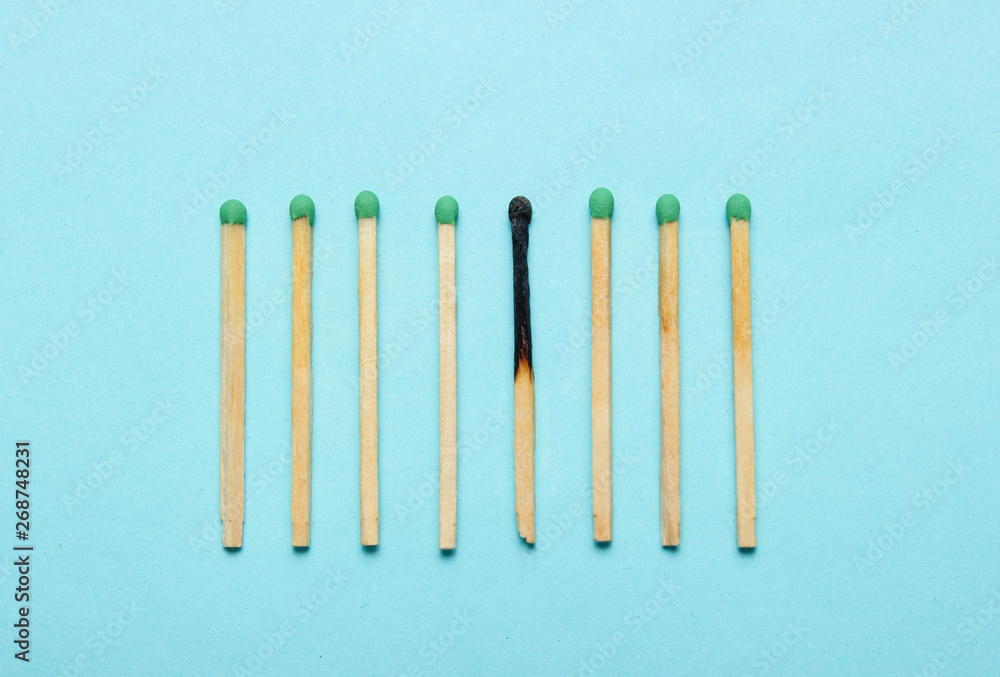 Burned and whole matches on a blue background. Minimalism concept Burned and whole matches on a blue background. Minimalism concept