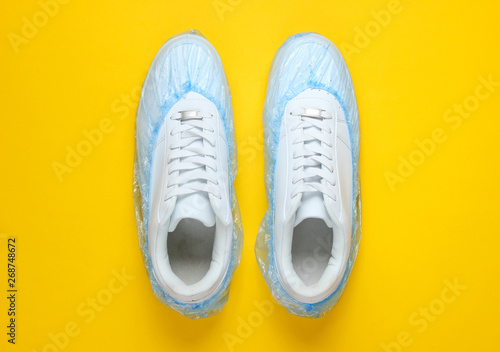 White sneakers in boot covers on a yellow background. Top view. Minimalism