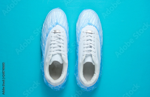 White sneakers in boot covers on blue background. Top view. Minimalism