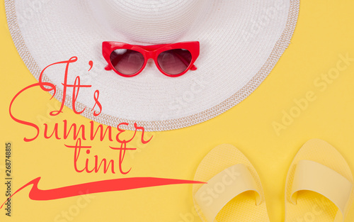 It's Summer Time text on yellow background, summer sandals, white hat and sunglasses.