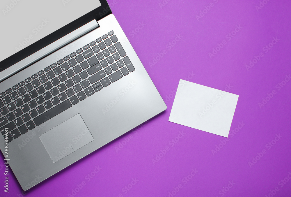 Modern laptop and sheet of white paper for copy space on a purple background. Top view Modern laptop and sheet of white paper for copy space on a purple background. Top view