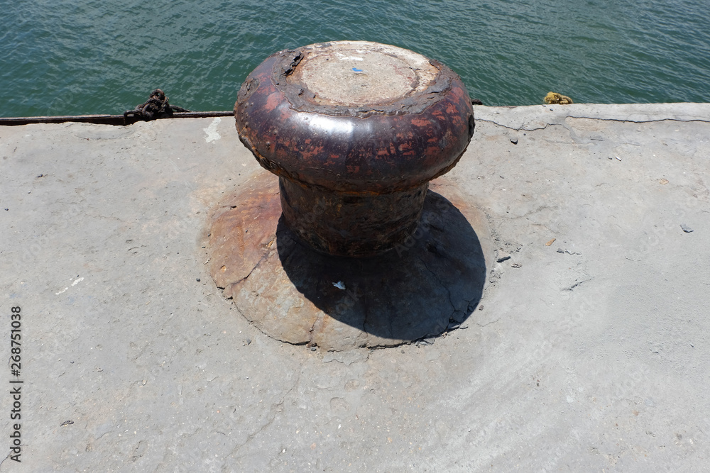 Rusty mooring bollard with ship ropes Rusty mooring bollard with ship ropes