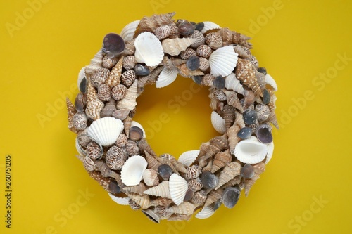 Home Decor in nautical style. wreath in the marine style of white and brown shells on a  yellow background.Sea summer concept. Summer vacation symbol
