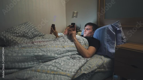 Man and women in bed distracted by their phones - technology - bored - married life - unsatisfied
