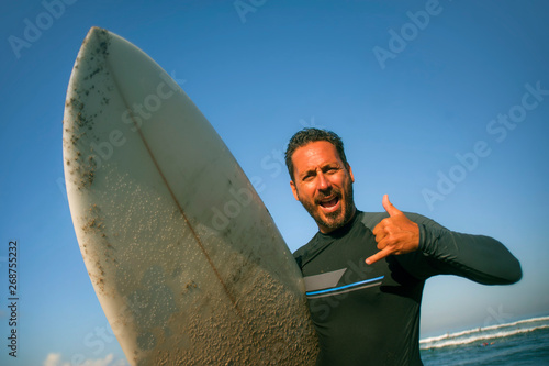 Photography natural portrait of attractive and happy surfer man on his 40s carrying surf boa
