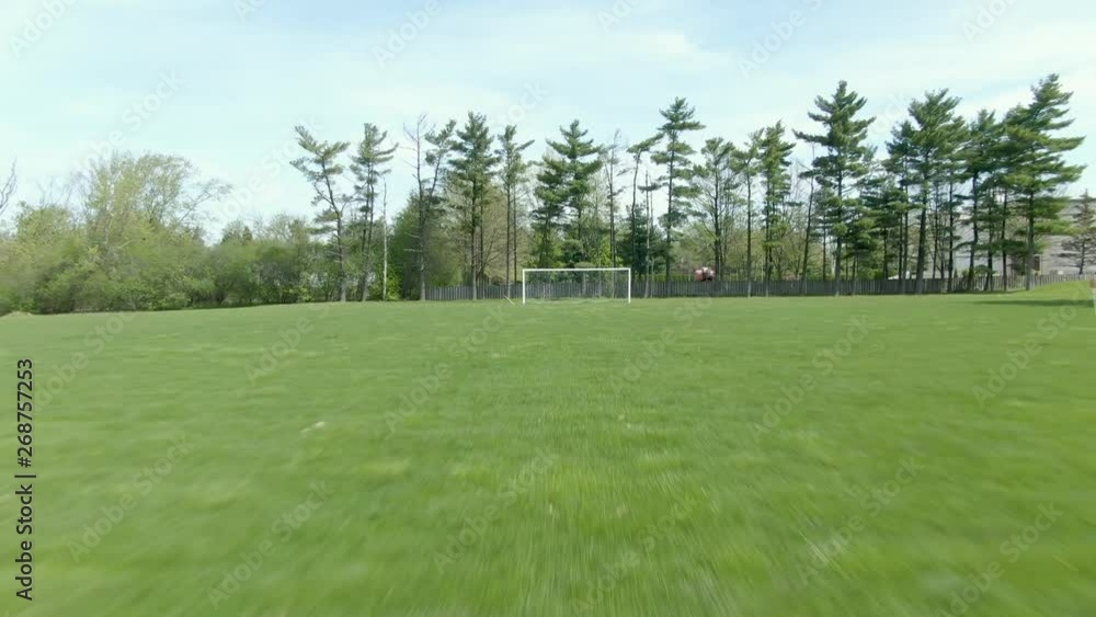 Reverse moving shot across a soccer field through a ripped part of the opposing net in the goal. No people, and a beautiful bright and sunny summer afternoon. Reverse moving shot across a soccer field through a ripped part of the opposing net in the goal. No people, and a beautiful bright and sunny summer afternoon.