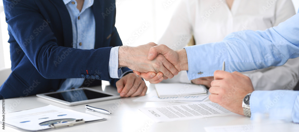 Business people shaking hands at meeting or negotiation, close-up. Group of unknown businessmen and women in modern office. Teamwork, partnership and handshake concept Business people shaking hands at meeting or negotiation, close-up. Group of unknown businessmen and women in modern office. Teamwork, partnership and handshake concept
