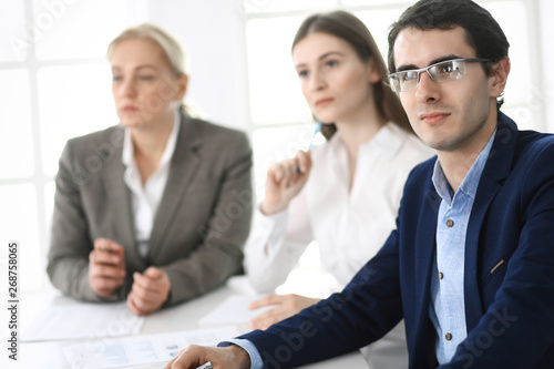 Group of business people discussing questions at meeting in modern office. Managers at negotiation or brainstorm. Teamwork, partnership and business concept