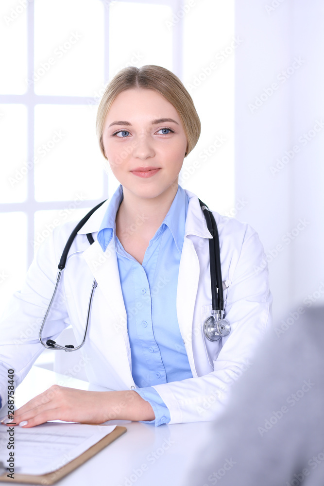 Young woman doctor and patient at medical examination at hospital office. Blue color blouse of therapist looks good. Medicine and healthcare concept Young woman doctor and patient at medical examination at hospital office. Blue color blouse of therapist looks good. Medicine and healthcare concept