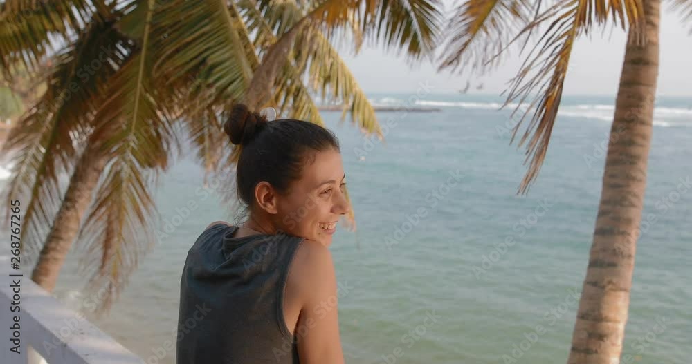 Young attractive girl with a flower in her hair enjoys the view of the ocean. tracking shot. in slow motion. Shot on Canon 1DX mark2 4K camera Young attractive girl with a flower in her hair enjoys the view of the ocean. tracking shot. in slow motion. Shot on Canon 1DX mark2 4K camera
